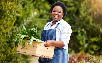 Smiling African woman farmer holding wooden crate of fresh organic leafy vegetables